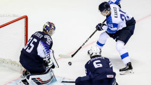 Kaapo Kakko med pucken framför USA:s mål, Jack Hughes försöker ta pucken av finländaren.