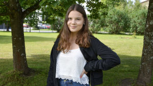 Julia-Sofie debuterade sommaren 2019 med låten Idiot. Artisten Julia Granholm med grönt gräs och gröna träd i bakgrunden.