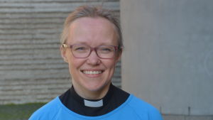 Malena Björkgren har saknat den fysiska kontakten med församlingen, och ser fram emot att få hålla gudstjänst framför Åbo svenska församling igen . Kvinna med prästkrage och ljusblå tunika som ler