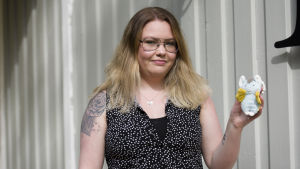 Josefine har köpt en ljusblå liten leksak. Josefine Stenvall håller upp en liten tygleksak