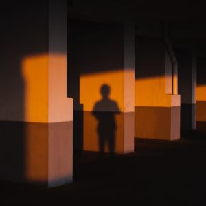 En mörk skugga av en person mot en orange betongvägg.
