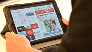 Västra Nyland finns kanske främst digitalt i framtiden. En person läser Västra Nyland på en pekplatta.