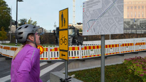 Satu Alaruikka stannar förbryllat när hon upptäcker att tunneln under Mannerheimvägen är avstängd. Cyklist tittar på skylt med karta