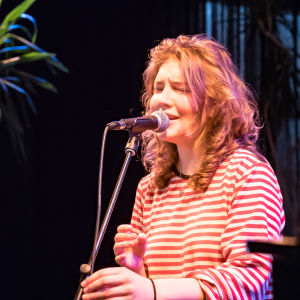En ung kvinna sjunger in i en mikrofon.