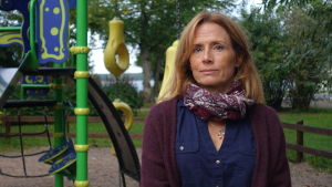 Charlotte Lindh bereder förslaget som ska förnya förskoleverksamheten. Charlotte Lindh står framför en klätterställning med gröna buskar och träd i bakgrunden. Hon har på sig en blå blus och en lila halsduk med mönster.