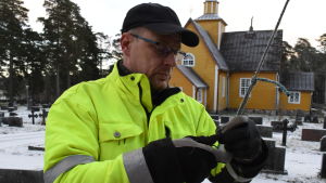 Janne Backas har tidigare år klättrat i granen själv, men nu står han på landbacken. Janne Backas håller i julgransbelysningen, i bakgrunden Dragsfjärds gula träkyrka.