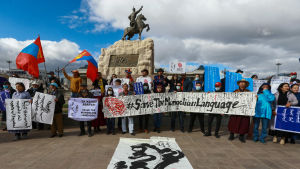 Demonstranter i Ulan Bator protesterar mot Kinas minoritetsförföljelser under den kinesiska utrikesministerns besök. I bakgrunden en staty av Mongoliets nationalhjälte Damdiny Süchbaatar som bekämpade både kinesiska och ryska trupper. Demonstranter i Ulan Bator håller upp banderoller med texten "Rädda det mongoliska språket".
