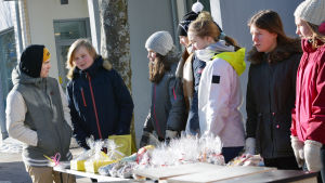 Åttondeklassare har bland annat gjort egna bakverk och sedan sålt dem på Karis torg. Det här för att se hur det är att vara företagare. Ett gäng med ungdomar står och säljer saker vid ett torgstånd.