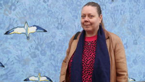 Eija Lang tycker att också finskspråkiga skulle kunna erbjudas gymnasieutbildning för att öka antalet elever. Eija Lang framför en blå vägg.
