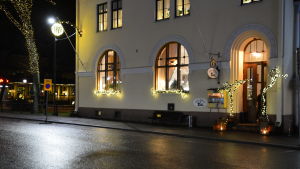 Sedan någon månad kan taxibilar också vänta på kunder vid stolpen utanför kaféet. Upplyst stenhus med juldekorationer.