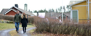 Oscar Gräsbeck kan jobba med sitt företag på distans i Bromarv. Ett ungt par går på en sandväg som går förbi ett stort gult trähus.