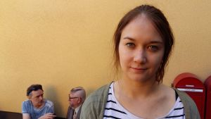 Emma Heino. I bakgrunden blir Kari Väänänen (Aulis Homelius) intervjuad. Emma Heino. I bakgrunden blir Kari Väänänen (Aulis Homelius) intervjuad.