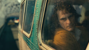 Joker utspelar sig i en förslummad sjuttiotalsinnerstad bland sopor och våld. Arthur (Joaquin Phoenix) sitter i en buss och tittar ut genom fönstret.