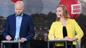 Katri Kulmuni (C) och Jussi Saramo från Vänsterförbundet. CenternsnKulmuni spänner ögonen i Vänsterförbundets Saramo, i bakgrunden röd reklamballong.