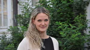 Mikaela Sundqvist. Närbild på Mikaela Sundqvist, utomhus vid en grön buske.