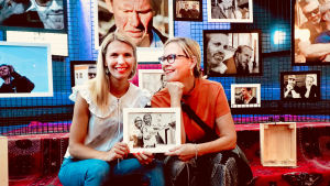 Eva och Linn fotograferar med genusglasögon. Linn Jung oh Eva Biauet sitter i fotogalleri med en bild på sig själva tillsammans i handen.