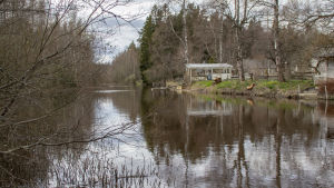 Vid åbryggorna brukar boendeföreningen årligen samlas för att lösa lokala ärenden, berättar en invånare i Myraskilen. Alla är inte av samma åsikt kring hur områdets framtid borde se ut. En å, hus och bryggor.