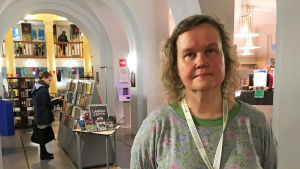 Ännu den här veckan kan man låna böcker på Berghälls bibliotek, bland annat av biblioteksfunktionär Anne Yli-Marttila. Biblioteksfunktionär Anne Yli-Marttila i Berghälls bibliotek, i bakgrunden bokhyllår och biblioteksbesökare.