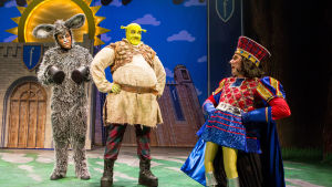 En tyrann och hans undersåtar. På bilden fr.v. Matti Leino som åsnan, Petrus Kähkönen som Shrek och Antti Timonen som Farquuad. Foto från Helsingfors stadsteaters uppsättning av musikalen Shrek.