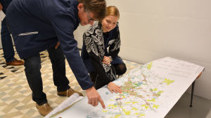 Tom Liljestrand (SFP) och Inka Kytö från Nylands förbund granskar kartor. personer ser på karta