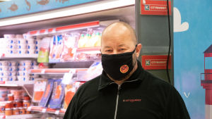 Köpmannen Marko Kindstedt säger att det går åt mycket fisk till jul. En man står i en butik vid fiskhyllan.
