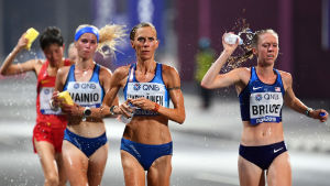 Anne-Mari Hyryläinen beskrev förhållandena i Doha som ganska omänskliga. Nu vill IOK undvika likadana minnen från OS. Alisa Vainio, Anne-Mari Hyryläinen och två andra maratonlöpare springer och förser sig med vatten samtidigt.