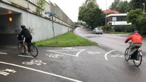 Vägen som går under gångtunneln leder till öns skolor. Två cyklister på cykelväg