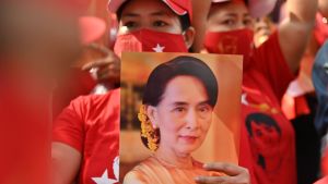Människor protesterar mot att Aung San Suu Kyi försatts i husarrest. En kvinna klädd i rött håller i en bild på Myanmars Aung San Suu Kyi