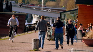 Längs åstranden i Borgå finns idag flera uteserveringar. Många minns Arne Roms välbesökta café. Mänskor ute på kvällspromenad.