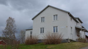 Rejpelt skola är byggd på 1800-talet och har inga dokumenterade problem med inomhusluften. Skolan uppskattas i byn för att den är liten, nära och står i lugn och naturnära miljö. Vitmålat trähus mot en bakgrund av regnmoln och vårgrönska.
