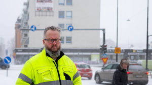 Underhållsmästare Ville Kaasinen i snöigt Borgå. En man i neonfärgad arbetsrock står framför en korsning, det snöar.