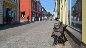 De mörkbruna träbänkarna i Gamla stan kommer kanske att bytas ut mot något med ännu äldre stil, säger man på Borgå stad. Bänkar i solsken vid kullerstensgata i Gamla stan.