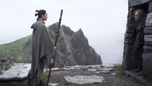 Luke, det är tid att stiga fram nu. Rey (Daisy Ridley) står utanför ett stenhus och ser på Luke Skywalker (Mark Hamill) som står i dörröppningen och inte vill umgås.