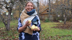 I sommar kommer en större del av lägerprogrammet ta plats utomhus, berättar Ungmarthas verksamhetsledare Elise Hindström. Arkivbild. Elise Hindström under äppelträd med äpplen i händerna.