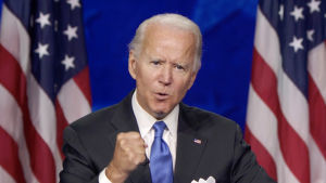 President Joe Biden driver på internationell skattereform. Joe Biden håller tal med usa:s flaggor i bakgrunden.