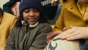 Tiana är med i "Min svarta lock" som handlar om hemlängtan. En flicka tittar på en person som spelar på en afrikansk trumma