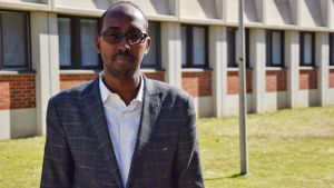 Liban Abdi Ali är i Finland och utbildas av Yle i vad det betyder att leda ett public service-bolag. En man står framför en tegelvägg på en gräsmatta.