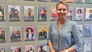 Virve Aho, sakkunnig i avtalsfrågor vid facket Super. Kvinna står framför en vägg med tidningar.