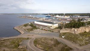 Regatta Resorts ska bygga bostäder på tomten som finns rakt framför stuveriföretagets vita byggnad som syns i mitten av bilden. Flygbild över Hangö där man ser Drottningberg och Västra hamnen.