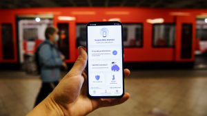 Coronablinkern lanserades i måndags. En hand håller upp en telefon med appen Coronablinkern, på en metroperrong.