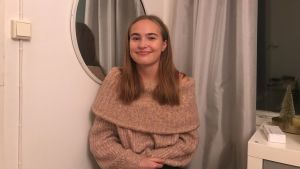 Sofia Eronen planerar att fortsätta med gymnasiestudier. En ung flicka med ljusbrunt hår och beige polotröja sitter vi en spegel och ler.