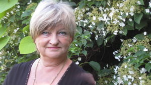 Irene Äyräväinen vill jobba mer med zonterapi och mindre med politik. En kvinna med grått hår och med en grön bakgrund bestående av växtlighet. Irene Äyräväinen heter hon.