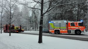 En bärgningsbil och en brandbil står vid en bil som varit med i en krock. Det är snö på marken.