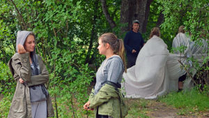 Från vänster. Livia Wikström och Emilia Tenhunen på scen. I bakgrunden Tobias Zilliacus med de underjordiska. Emilia Tenhunen står och pratar med Livia Wikström. I bakgrunden Tobias Zilliacus med de underjordiska.