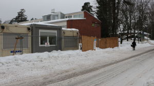 Mäntymäen koulu ligger på andra sidan vägen från Grankulla FBK. Mäntymäen koulus byggnad med byggmaterial och i förgrunden.