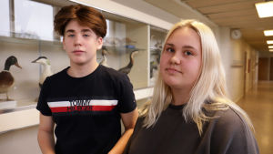 Niondeklassarna Eddie Grönholm och Amanda Jacobsson i Hangö tycker de lokala matbutikernas varierande inställning till energidrycker är förvirrande. Två högstadieelever på nian står i en tom skolkorridor och ser mot kameran.