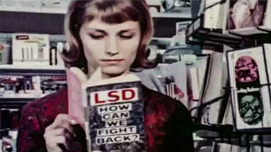 Docventures: Neurons to Nirvana. Nainen lukee kirjaa, jossa lukee LSD, How can we fight back.