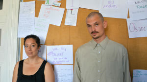 Emily Al-Ghussein och Fabian Olovson arbetar mycket med listor och mindmaps, som de hänger upp på ateljéns väggar. En kvinna och en man står framför en anslagstavla och tittar in i kameran.