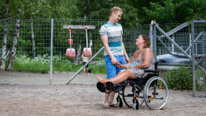 Vakuutusetsivien seurannan kohteeksi joutunut Sofia Tuomi istuu pyörätuolissa ja pitää kädestä aviopuolisoaan Oskari Tuomea. 