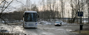Området bakom de parkerade fordonen kan bli en hundpark i framtiden. En lerig parkering där en buss och en personbil står parkerade. I bakgrunden skymtar stora högar med snö.